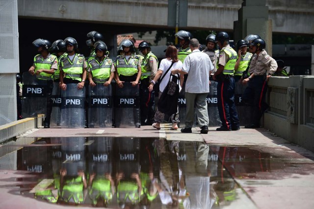 Venezuelan police in riot gear remain on standby in Caracas, on April 22, 2017. Venezuelans gathered Saturday for "silent marches" against President Nicolas Maduro, a test of his government's tolerance for peaceful protests after three weeks of violent unrest that has left 20 people dead. / AFP PHOTO / RONALDO SCHEMIDT