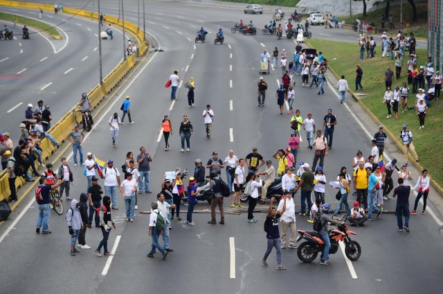 Venezuelan opposition activists block the Francisco Fajardo motorway in Caracas, on April 24, 2017. Protesters plan Monday to block Venezuela's main roads including the capital's biggest motorway, triggering fears of further violence after three weeks of unrest left 21 people dead. / AFP PHOTO / RONALDO SCHEMIDT