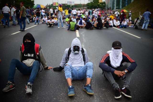 Venezuelan opposition activists block organize a sit-in to block the Francisco Fajardo motorway in Caracas, on April 24, 2017. Protesters plan Monday to block Venezuela's main roads including the capital's biggest motorway, triggering fears of further violence after three weeks of unrest left 21 people dead. / AFP PHOTO / RONALDO SCHEMIDT