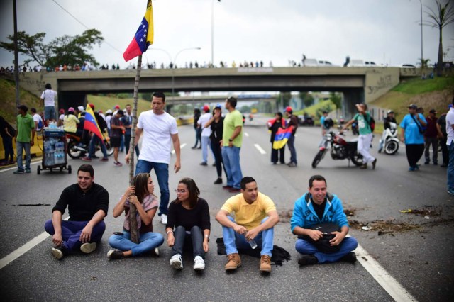 Venezuelan opposition activists block organize a sit-in to block the Francisco Fajardo motorway in Caracas, on April 24, 2017. Protesters plan Monday to block Venezuela's main roads including the capital's biggest motorway, triggering fears of further violence after three weeks of unrest left 21 people dead. / AFP PHOTO / RONALDO SCHEMIDT