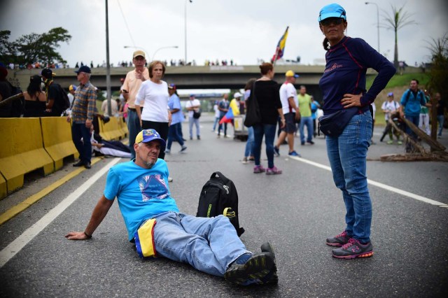 Venezuelan opposition activists block organize a sit-in to block the Francisco Fajardo motorway in Caracas, on April 24, 2017. Protesters plan Monday to block Venezuela's main roads including the capital's biggest motorway, triggering fears of further violence after three weeks of unrest left 21 people dead. / AFP PHOTO / RONALDO SCHEMIDT