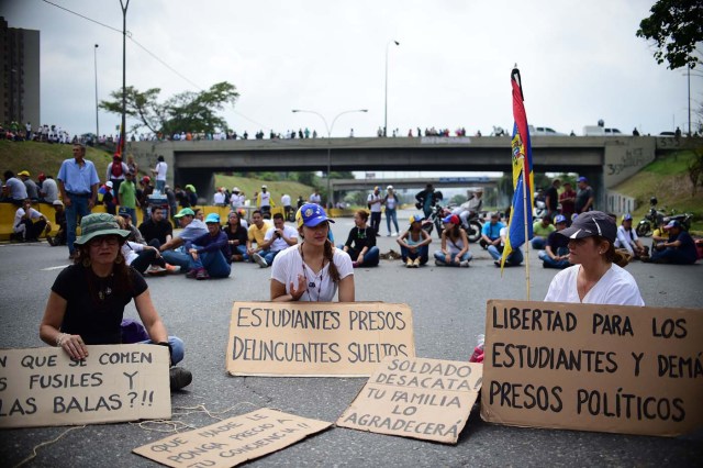 Venezuelan opposition activists block organize a sit-in to block the Francisco Fajardo motorway in Caracas, on April 24, 2017. Protesters plan Monday to block Venezuela's main roads including the capital's biggest motorway, triggering fears of further violence after three weeks of unrest left 21 people dead. / AFP PHOTO / RONALDO SCHEMIDT