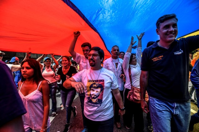 The first vice-president of Venezuela's National Assembly, Freddy Guevara (C), joins opposition activists marching against President Nicolas Maduro in Caracas, on April 24, 2017. Protesters rallied on Monday vowing to block Venezuela's main roads to raise pressure on Maduro after three weeks of deadly unrest that have left 21 people dead. Riot police fired rubber bullets and tear gas to break up one of the first rallies in eastern Caracas early Monday while other groups were gathering elsewhere, the opposition said. / AFP PHOTO / Juan BARRETO