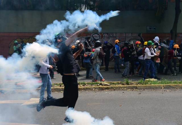 Venezuelan opposition activists clash with the police during a march against President Nicolas Maduro, in Caracas on May 1, 2017. Security forces in riot vans blocked off central Caracas Monday as Venezuela braced for pro- and anti-government May Day protests one month after a wave of deadly political unrest erupted.  / AFP PHOTO / RONALDO SCHEMIDT