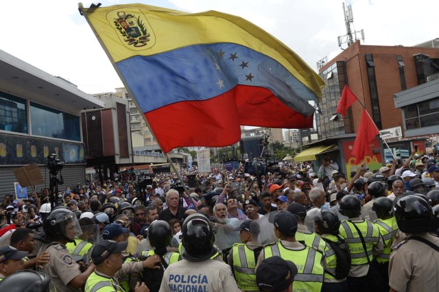 Opposition activists confront riot police during a protest against the government in Caracas on May 12, 2017. Daily clashes between demonstrators -who blame elected President Nicolas Maduro for an economic crisis that has caused food shortage- and security forces have left 38 people dead since April 1. Protesters demand early elections, accusing Maduro of repressing protesters and trying to install a dictatorship.  / AFP PHOTO / FEDERICO PARRA