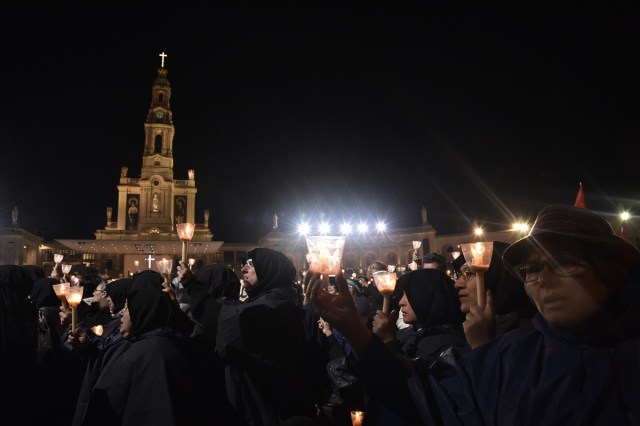 Pilgrims hold candles at the Shrine of Fatima during the Blessing for the Candles from the Chapel of the Apparitions by Pope Francis, in Fatima on May 12, 2017. Two of the three child shepherds who reported apparitions of the Virgin Mary in Fatima, Portugal, one century ago, will be declared saints on May 13, 2017 by Pope Francis. The canonisation of Jacinta and Francisco Marto will take place during the Argentinian pontiff's visit to a Catholic shrine visited by millions of pilgrims every year. / AFP PHOTO / TIZIANA FABI