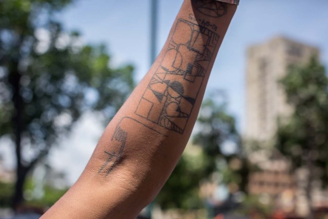 ACOMPAÑA CRÓNICA: VENEZUELA CRISIS. CAR12. CARACAS (VENEZUELA), 20/05/2017.- Un manifestante muestra su brazo con la firma del presidente Hugo Chávez tatuada hoy, sábado 20 de mayo de 2017, en Caracas (Venezuela). Con rostros que revelan que crecieron bajo la revolución que desde 1999 vive Venezuela, los milenials, sin distingo de clases y el entusiasmo propio de su edad, se han convertido en la vanguardia de las manifestaciones que desde hace 50 días mantiene la oposición en contra del presidente Nicolás Maduro. EFE/Miguel Gutiérrez