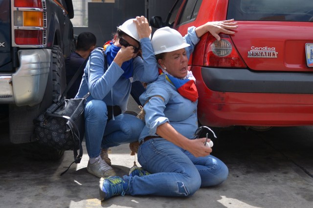 Health workers are affected by tear gas in clashes with the riot police during the "Towards Victory" protest against the government of Nicolas Maduro, in Caracas on June 10, 2017.  Clashes at near daily protests by demonstrators calling for Maduro to quit have left 66 people dead since April 1, prosecutors say.  / AFP PHOTO / LUIS ROBAYO