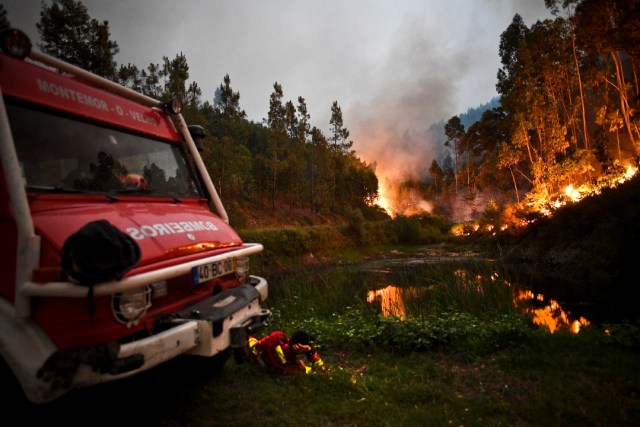 A firefighter rests next to fire combat truck during a wildfire at Penela, Coimbra, central Portugal, on June 18, 2017.  A wildfire in central Portugal killed at least 25 people and injured 16 others, most of them burning to death in their cars, the government said on June 18, 2017. Several hundred firefighters and 160 vehicles were dispatched late on June 17 to tackle the blaze, which broke out in the afternoon in the municipality of Pedrogao Grande before spreading fast across several fronts.    / AFP PHOTO / PATRICIA DE MELO MOREIRA