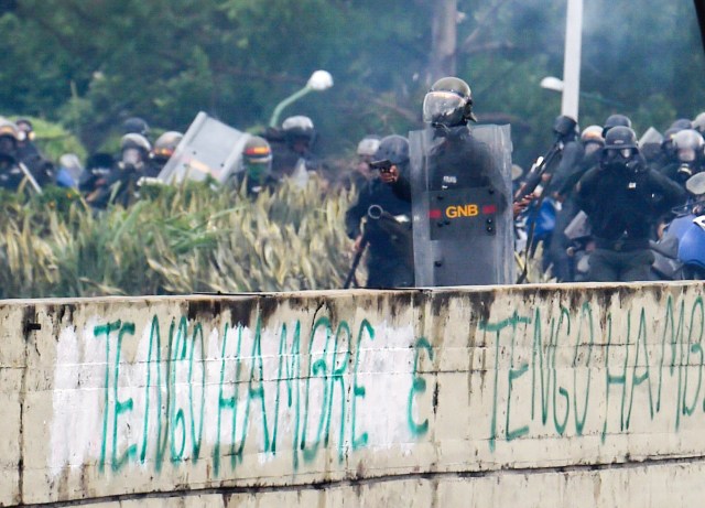 A member of the National Guard holds a gun during clashes with opposition activists demonstrating against the government of President Nicolas Maduro along the Francisco Fajardo highway in Caracas on June 19, 2017. Near-daily protests against President Nicolas Maduro began on April 1, with demonstrators demanding his removal and the holding of new elections. The demonstrations have often turned violent with 73 people killed and more than 1,000 injured so far, prosecutors say, and more than 3,000 arrested, according to the NGO Forum Penal.  / AFP PHOTO / Juan BARRETO