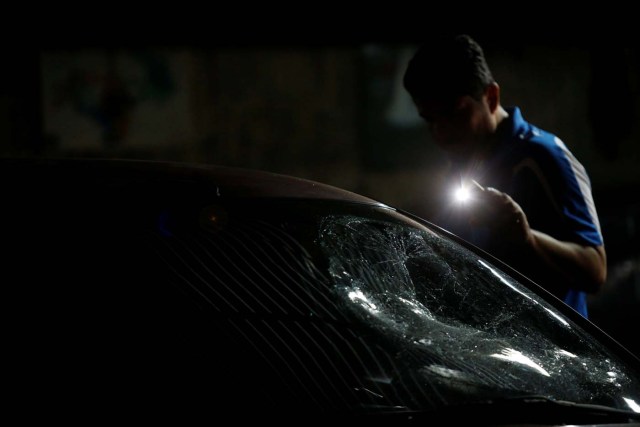 A man in a garage inspects a car with a shattered window, after opposition supporters and security forces clashed in and outside the building on Tuesday according to residents, in Caracas, Venezuela June 14, 2017. REUTERS/Ivan Alvarado