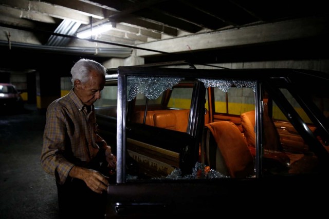 A man stands in a garage and next to a car with a shattered window after opposition supporters and security forces clashed in and outside the building on Tuesday according to residents, in Caracas, Venezuela June 14, 2017. REUTERS/Ivan Alvarado