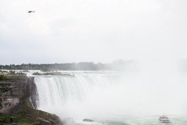 Aerialist Erendira Wallenda hangs beneath a helicopter during a stunt over the Horseshoe Falls at Niagara Falls, New York, June 15, 2017. / AFP PHOTO / Geoff Robins