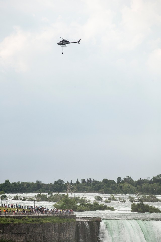 Aerialist Erendira Wallenda hangs beneath a helicopter during a stunt over the Horseshoe Falls at Niagara Falls, New York, June 15, 2017. / AFP PHOTO / Geoff Robins