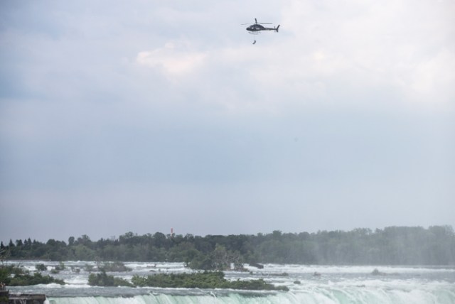 Aerialist Erendira Wallenda hangs beneath a helicopter during a stunt over the Horseshoe Falls at Niagara Falls, New York, June 15, 2017. / AFP PHOTO / Geoff Robins