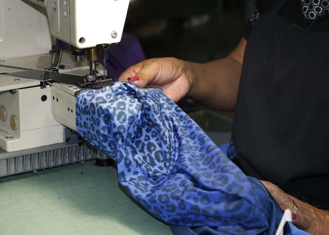 Maribel Cruz works on clothing for Venezuelan artist and designer Lisu Veg collection "Resistance" in a warehouse in Miami, Florida on June 8, 2017. The models are dressed in scenes of violence in Caracas and handkerchiefs representing the rags used by protesters to protect themselves from police tear gas. It is the "Resistance" collection of Venezuelan fashion designer Lisu Vega. / AFP PHOTO / RHONA WISE