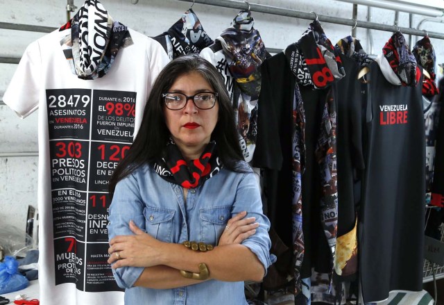 Venezuelan artist and designer Lisu Vega poses in front of her collection "Resistance" in a warehouse in Miami, Florida on June 8, 2017. The models are dressed in scenes of violence in Caracas and handkerchiefs representing the rags used by protesters to protect themselves from police tear gas. It is the "Resistance" collection of Venezuelan fashion designer Lisu Vega. / AFP PHOTO / RHONA WISE