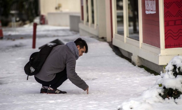 A touches snow in Santiago on July 15, 2017.  An unusual snowfall --the first of such intensity since 2007-- surprised the inhabitants of the Chilean capital, causing a few power cuts and minor traffic jams, in particular in the eastern areas of the capital, the closest to the Andes mountain range. / AFP PHOTO / MARTIN BERNETTI