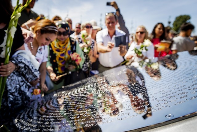 Relatives attend the unveiling of the National Monument for the MH17 victims in Vijfhuizen, on July 17, 2017.  Three years after Flight MH17 was shot down by a missile over war-torn Ukraine, more than 2,000 relatives gather to unveil a "living memorial" to their loved ones. A total of 298 trees have been planted in the shape of a green ribbon, one for each of the victims who died on board the Malaysia Airlines flight en route from Amsterdam to Kuala Lumpur. The flowers also represent "the sunflower fields in eastern Ukraine where some parts of the plane wreckage were found". / AFP PHOTO / ANP / Remko de Waal / Netherlands OUT