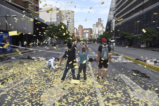 Youngsters throw on the avenue unused subway tickets during an anti-government protest in Caracas, on July 20, 2017. A 24-hour nationwide strike got underway in Venezuela Thursday, in a bid by the opposition to increase pressure on beleaguered leftist President Nicolas Maduro following four months of deadly street demonstrations. / AFP PHOTO / JUAN BARRETO