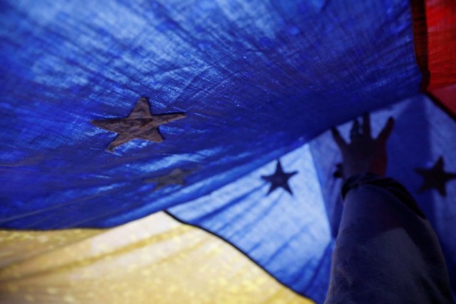 An opposition supporter touches a Venezuelan flag during a vigil in homage to victims of violence at past protests against Venezuela's President Nicolas Maduro's government in Caracas, Venezuela, July 13, 2017. REUTERS/Andres Martinez Casares