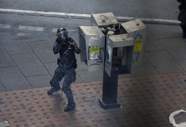 Un miembro de las fuerzas de seguridad de Venezuela apunta su arma durante enfrentamientos con manifestantes opositores en Caracas. 30 de julio de 2017. REUTERS/Carlos García Rawlins