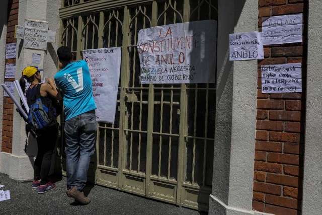 CAR12. CARACAS (VENEZUELA), 24/07/2017.- Manifestantes pegan carteles en rechazo a la Asamblea Constituyente hoy, lunes 24 de julio de 2017, en un colegio electoral de Caracas (Venezuela). Venezuela inicia hoy la semana decisiva para la elección de la Asamblea Nacional Constituyente convocada por el presidente, Nicolás Maduro, con los oficialistas entrando en la recta final de su campaña en medio de protestas y llamados a paro de los opositores en rechazo a esos comicios. EFE/Miguel Gutiérrez