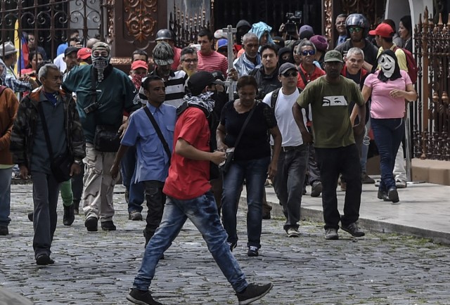 Supporters of Venezuelan President Nicolas Maduro storm the National Assembly building in Caracas on July 5, 2017 as opposition deputies hold a special session on Independence Day. A political and economic crisis in the oil-producing country has spawned often violent demonstrations by protesters demanding President Nicolas Maduro's resignation and new elections. The unrest has left 91 people dead since April 1. / AFP PHOTO / Juan BARRETO