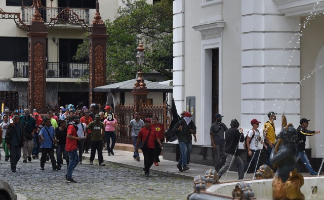 Supporters of Venezuelan President Nicolas Maduro storm the National Assembly building in Caracas on July 5, 2017 as opposition deputies hold a special session on Independence Day. A political and economic crisis in the oil-producing country has spawned often violent demonstrations by protesters demanding President Nicolas Maduro's resignation and new elections. The unrest has left 91 people dead since April 1. / AFP PHOTO / Juan BARRETO