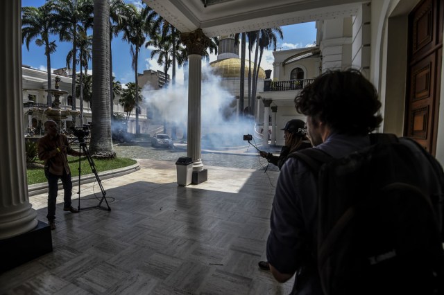 Journalists react as supporters of Venezuelan President Nicolas Maduro storm into the National Assembly building in Caracas on July 5, 2017 as opposition deputies hold a special session on Independence Day. A political and economic crisis in the oil-producing country has spawned often violent demonstrations by protesters demanding President Nicolas Maduro's resignation and new elections. The unrest has left 91 people dead since April 1. / AFP PHOTO / Juan BARRETO