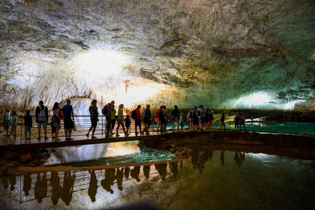 People visit the natural cave of Choranche, in the Vercors region near Grenoble, on August 3, 2017. Since the beginning of the heat wave, there has been an increase of at least 10 percent in the number of cave visitors, looking for beautiful natural sites, but also for underground freshness with temperatures around 15 Degrees Celsius. / AFP PHOTO / JEAN-PIERRE CLATOT