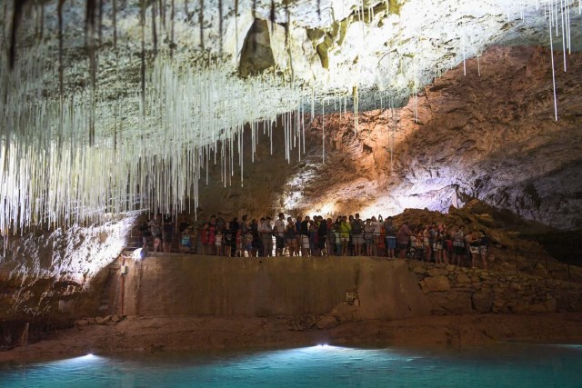 People visit the natural cave of Choranche, in the Vercors region near Grenoble, on August 3, 2017. Since the beginning of the heat wave, there has been an increase of at least 10 percent in the number of cave visitors, looking for beautiful natural sites, but also for underground freshness with temperatures around 15 Degrees Celsius. / AFP PHOTO / JEAN-PIERRE CLATOT