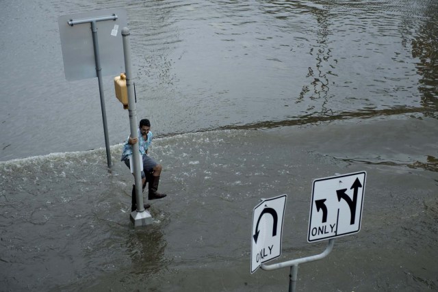 A man dodges a wake in flood waters during the aftermath of Hurricane Harvey August 27, 2017 in Houston, Texas. Hurricane Harvey left a trail of devastation after the most powerful storm to hit the US mainland in over a decade slammed into Texas, destroying homes, severing power supplies and forcing tens of thousands of residents to flee. / AFP PHOTO / Brendan Smialowski