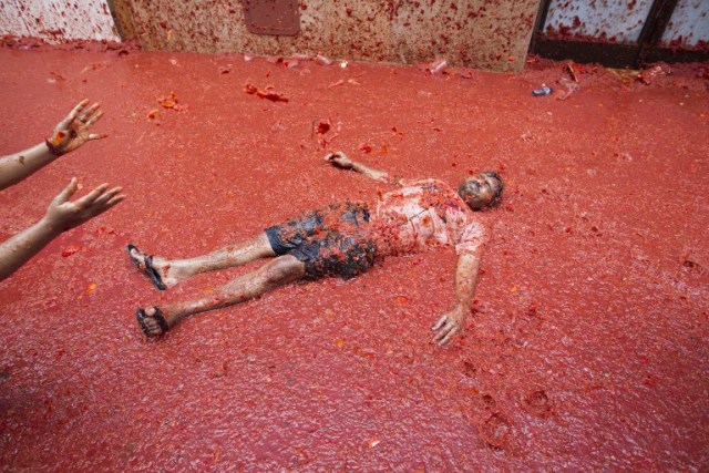 A reveller covered in tomato pulp takes part in the annual "Tomatina" festival in the eastern town of Bunol, on August 30, 2017. The iconic fiesta -- which celebrates its 72nd anniversary and is billed at "the world's biggest food fight" -- has become a major draw for foreigners, in particular from Britain, Japan and the United States. / AFP PHOTO / JAIME REINA