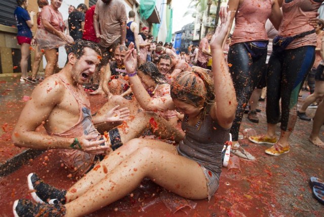 Revellers covered in tomato pulp take part in the annual "Tomatina" festival in the eastern town of Bunol, on August 30, 2017. The iconic fiesta -- which celebrates its 72nd anniversary and is billed at "the world's biggest food fight" -- has become a major draw for foreigners, in particular from Britain, Japan and the United States. / AFP PHOTO / JAIME REINA