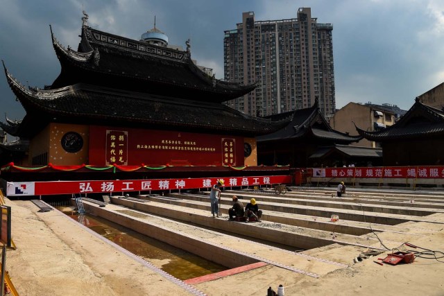 (FILES) This file picture taken on September 5, 2017 shows construction personnel working to relocate the main hall of the 135-year old Yufo Temple, also known as the Jade Buddha Temple, in Shanghai. The main hall and statues of the temple in central Shanghai have been moved 30 metres (100 feet) on rails to ease crowding at the popular site. / AFP PHOTO / Chandan KHANNA