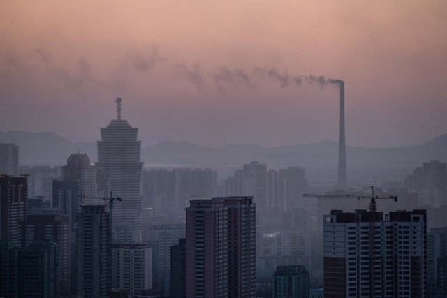 (FILES) A file photo taken on February 17, 2017 shows the chimney of a power station amid the Pyongyang city skyline. North Korea suffers from perennial energy shortages, epitomised by satellite photos of the country at night, showing it as a largely dark quadrilateral between the bright lights of China and the South. / AFP PHOTO / ED JONES / TO GO WITH: NKorea-economy-electricity-politics, FOCUS by Sebastien BERGER