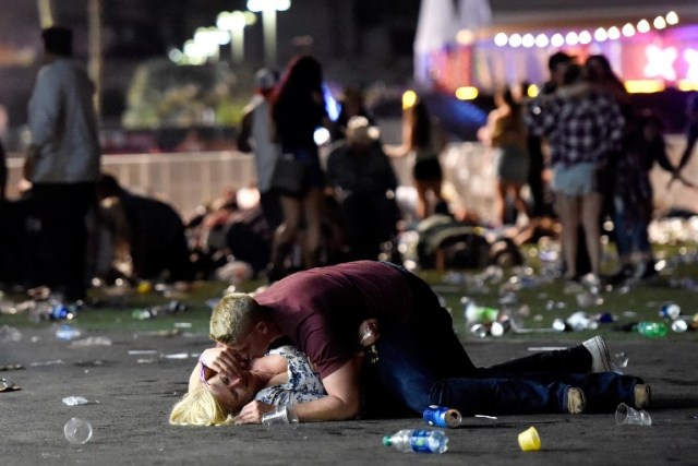 LAS VEGAS, NV - 01 de octubre: Un hombre se pone encima de una mujer como otros huyen de los motivos del festival de música country de la cosecha de la Ruta 91 después de que un tirador activo fue informado el 1 de octubre de 2017 en Las Vegas, Nevada. Un pistolero abrió fuego en un festival de música en Las Vegas, dejando al menos 2 muertos. La policía ha confirmado que un sospechoso ha recibido un disparo. La investigación está en curso. David Becker / Getty Images / AFP