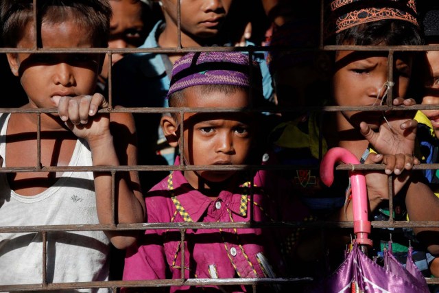 Students of a local madrasa watch from inside their classroom as bodies of Rohingya refugees from Myanmar, who were killed when their boat capsized on the way to Bangladesh, are brought to their school in Shah Porir Dwip, in Teknaf, near Cox's Bazar in Bangladesh, October 9, 2017. REUTERS/Damir Sagolj