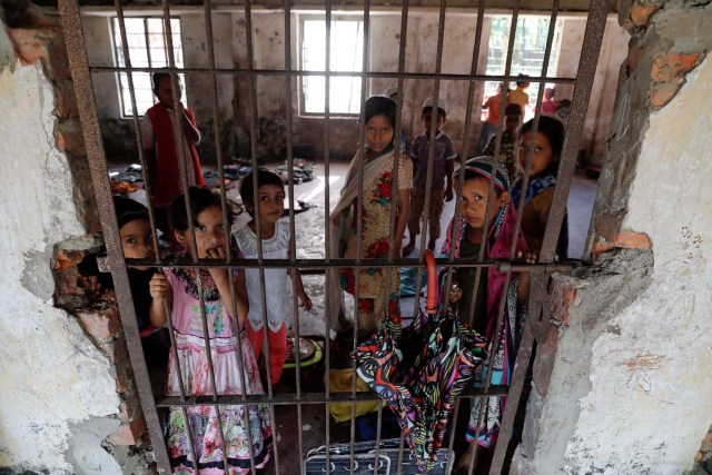 Students of a local madrasa watch from inside their classroom as bodies of Rohingya refugees from Myanmar, who were killed when their boat capsized on the way to Bangladesh, are brought to their school in Shah Porir Dwip, in Teknaf, near Cox's Bazar in Bangladesh, October 9, 2017. REUTERS/Damir Sagolj