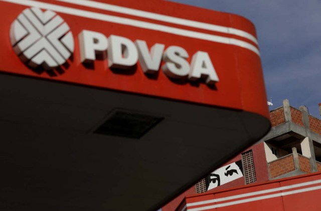 A painting depicting the eyes of Venezuela's late President Hugo Chavez, is pictured close to a corporate logo of the state oil company PDVSA at a gas station in Caracas, Venezuela, October 10, 2017. Picture taken October 10, 2017. REUTERS/Ricardo Moraes