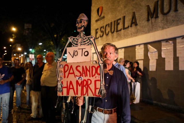 -FOTODELDIA- VEN02. CARACAS (VENEZUELA), 15/10/2017.- Un hombre camina con un esqueleto a modo de protesta durante el cierre de las mesas de votación hoy, domingo 15 de octubre de 2017, en un centro electoral de Caracas (Venezuela). Este domingo la oposición y el chavismo se midieron por las 23 gobernaciones del país en unos comicios en los que estuvieron llamados a participar poco más de 18 millones de votantes. EFE/Miguel Gutiérrez