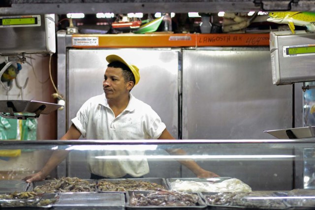 A seafood seller waits for customers at the municipal market of Chacao in Caracas on November 2, 2017. This week, Venezuelan President Nicolas Maduro introduced a new bank note of 100,000 Bolivars - five times the current largest denomination - and announced a 30 percent minimum wage hike. / AFP PHOTO / FEDERICO PARRA