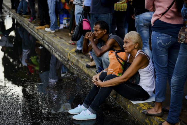 People queue at a bus stop in Catia, a neighbourhood of Caracas, on November 1, 2017. People queue for upto four hours to take a bus home in Venezuela, where mobilizing by land or plane has become a headache. / AFP PHOTO / Federico PARRA