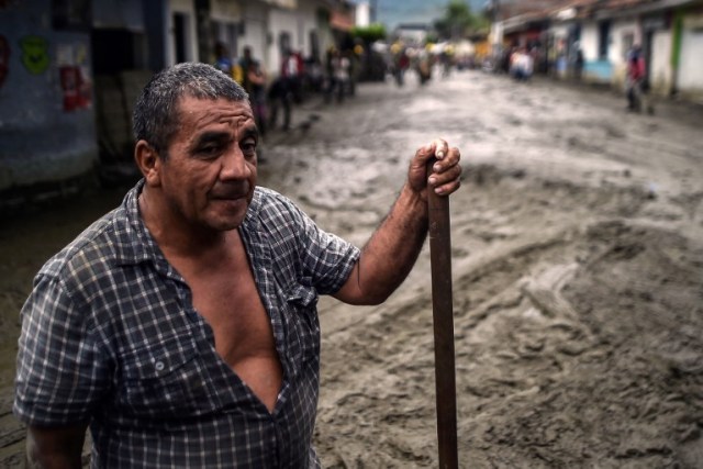 Un hombre se para en medio de una calle embarrada después de un alud debido a las fuertes lluvias que afectaron a Corinto en el departamento de Cauca, al suroeste de Colombia el 8 de noviembre de 2017. El deslizamiento de tierra afectó a Corinto el martes por la noche, dejando tres muertos, 32 heridos y 18 desaparecidos, además de cientos de viviendas afectadas, según el último balance proporcionado por las autoridades. / AFP PHOTO / LUIS ROBAYO