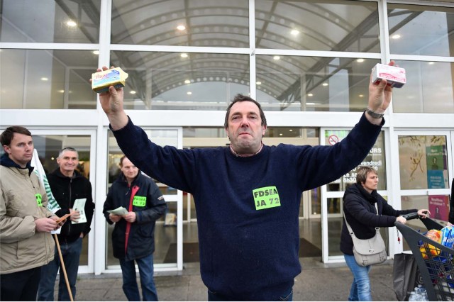 French farmer Ghislain De Viron (C) presents butter made from a blend of European Union milk as a substitute for French butter in front of the hyper market Leclerc d'Alllonnes, near Le Mans, northwestern France, on November 10, 2017 during an action to sell butter at a price that will remunerate them. / AFP PHOTO / JEAN-FRANCOIS MONIER