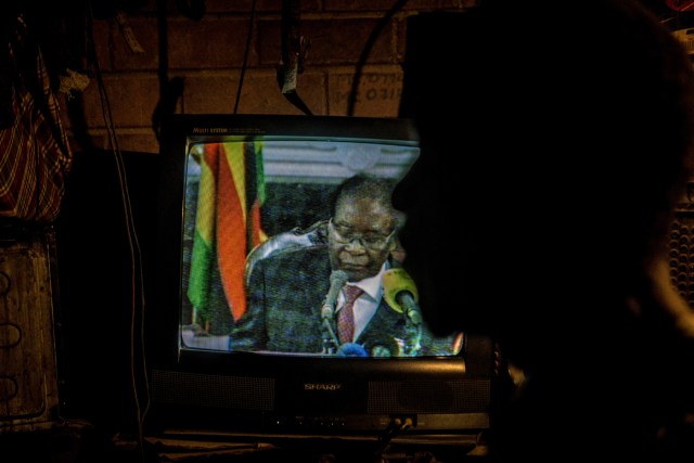 A man looks at a television set broadcasting a state address by Zimbabwe's President Robert Mugabe in Mbare, Harare on November 19, 2017.  Zimbabwean President Robert Mugabe, in a much-expected TV address, stressed he was still in power after his authoritarian 37-year reign was rocked by a military takeover. Many Zimbabweans expected Mugabe to resign after the army seized power last week. But Mugabe delivered his speech alongside the uniformed generals who were behind the military intervention. In his address, Mugabe made no reference to the clamour for him to resign. / AFP PHOTO / ZINYANGE AUNTONY