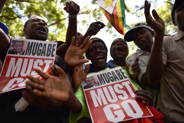 Anti-Zimbabwe President hold placards during a gathering at Unity square, on November 21, 2017 in the capital Harare, praying and asking for Mugabe's impeachment, as Parliament prepares to start impeachment proceedings against the President, while ousted vice president who could be the country's next leader, tells him to step down. As the 93-year-old autocrat faced intensifying pressure to quit, southern Africa's regional bloc announced it was dispatching the presidents of Angola and South Africa to Harare to discuss the crisis. / AFP PHOTO / Tony KARUMBA