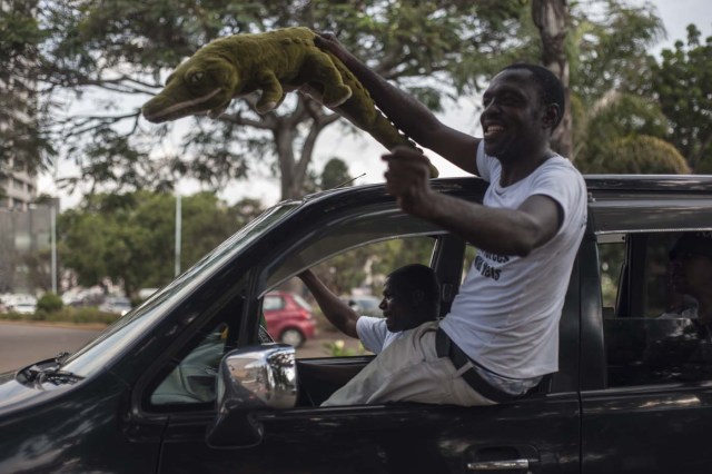 A Zimbabwean holds a crocodile soft toy as he celebrates from a car the arrival of Zimbabwe's ousted vice president Emmerson Mnangagwa, at the headquarters of Zimbabwe's African National Union Patriotic Front (ZANU PF) party in Harare, on November 22, 2017. / AFP PHOTO / STEFAN HEUNIS