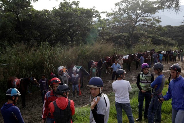 Jockeys wait with their horses to attend a training session at La Rinconada Hippodrome, in Caracas, Venezuela, October 7, 2017. REUTERS/Ricardo Moraes SEARCH "MORAES GAMBLING" FOR THIS STORY. SEARCH "WIDER IMAGE" FOR ALL STORIES.